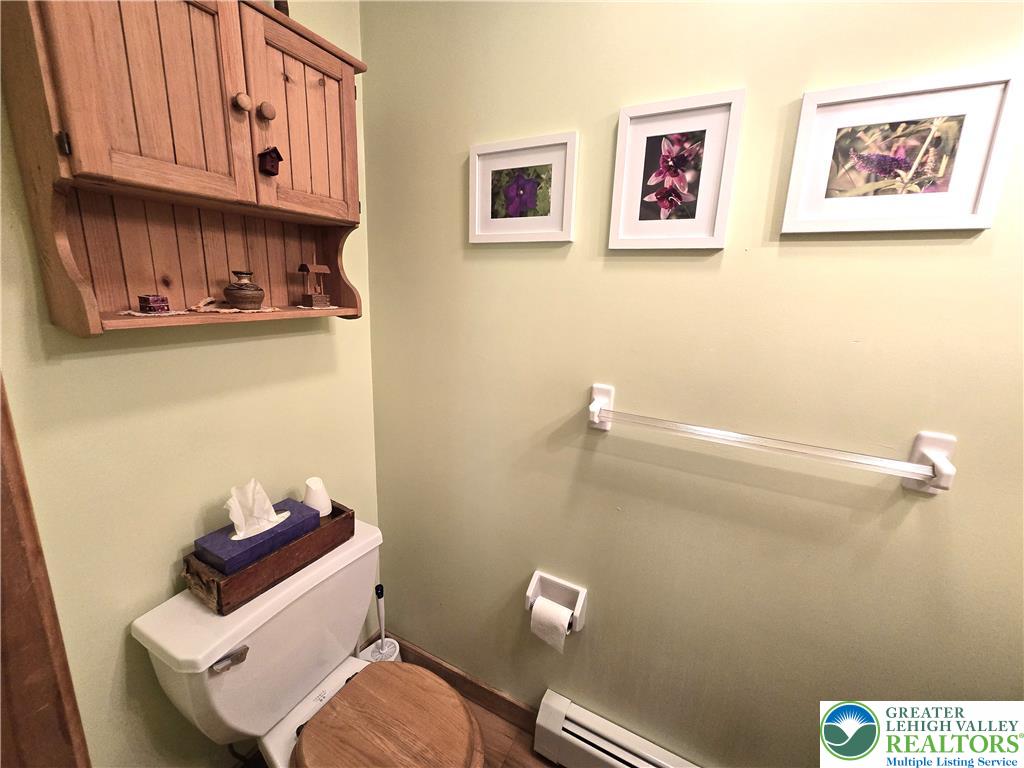 477 Quiet Valley Road Mount Bethel, PA 18343 - Photo 35 of 53 A compact bath space features a wooden wall cabinet above the toilet and soft green walls.