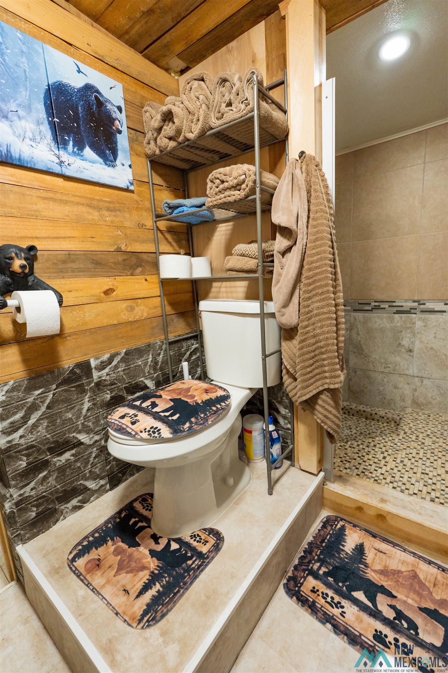 3 Wimsatt Road Cloudcroft, NM 88317 - Photo 24 of 41 Bathroom featuring tiled shower, wooden walls, and tile patterned flooring
