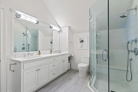 a spacious bathroom with a double vanity sink toilet mirror and shower