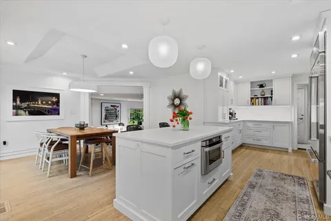 a kitchen that has a lot of white cabinets and stainless steel appliances