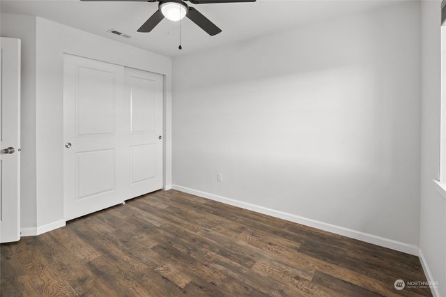 a view of empty room with wooden floor and fan