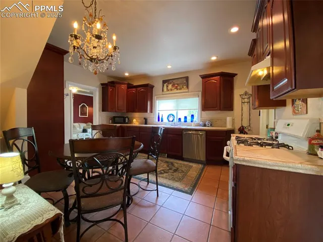 a kitchen with stainless steel appliances granite countertop a sink dishwasher a stove a refrigerator a dining table and chairs with wooden floor