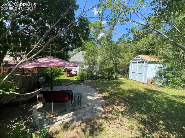 a backyard of a house with table and chairs under an umbrella