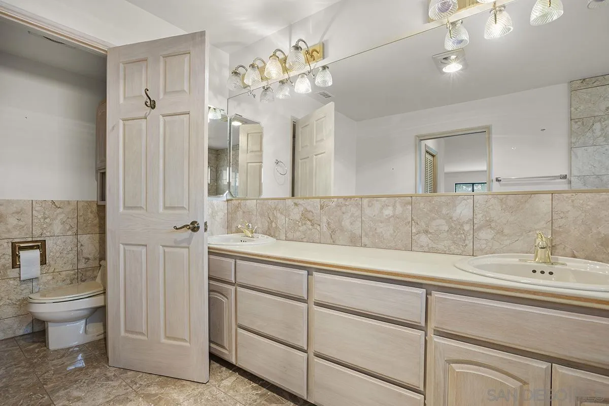 3130 Goldfinch Street San Diego, CA 92103 - Photo 39 of 59 a spacious bathroom with a double vanity sink a large mirror and a toilet