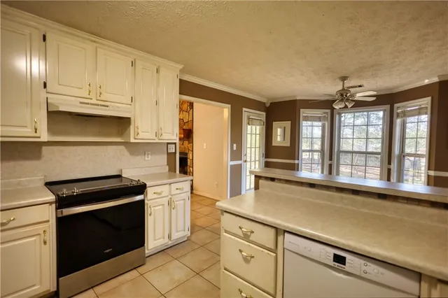 a kitchen with stainless steel appliances granite countertop a refrigerator a sink a stove and white cabinets