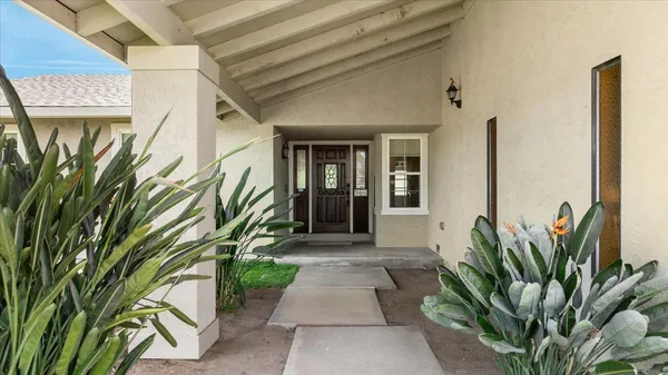 an empty room with windows and view of kitchen