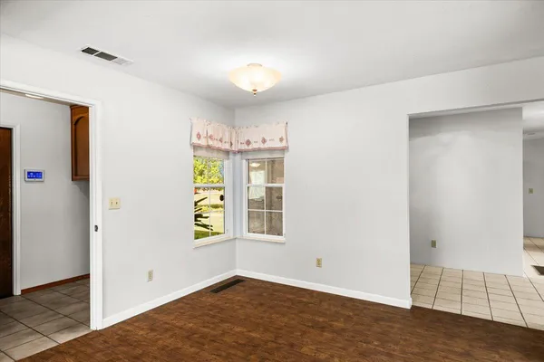 an empty room with windows and chandelier fan