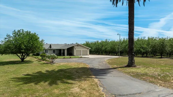 an aerial view of a residential houses with outdoor space and trees