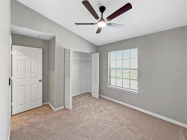 an empty room with windows and fan
