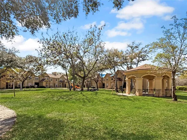 a view of a white house with a big yard and large trees