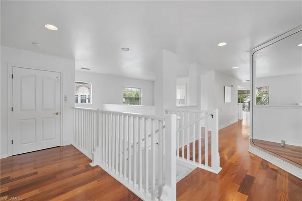 a view of a hallway with wooden floor and windows