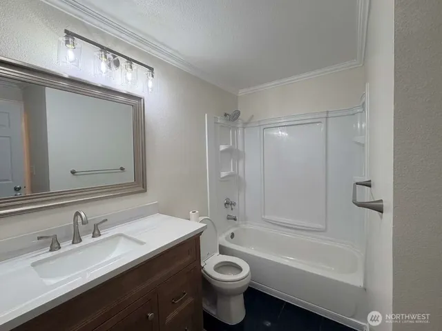 a bathroom with a granite countertop sink a toilet a mirror and bathtub