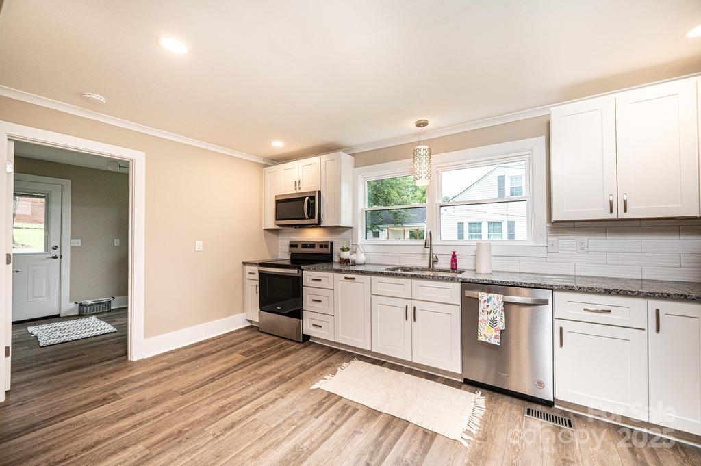 1105 Wildwood Road Lenoir, NC 28645 - Photo 15 of 38 a kitchen with stainless steel appliances granite countertop a stove top oven a sink dishwasher and white cabinets with wooden floor