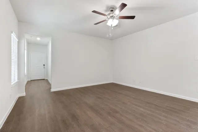 an empty room with wooden floor and a ceiling fan
