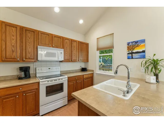a kitchen with stainless steel appliances granite countertop a sink a stove a refrigerator cabinets and a window