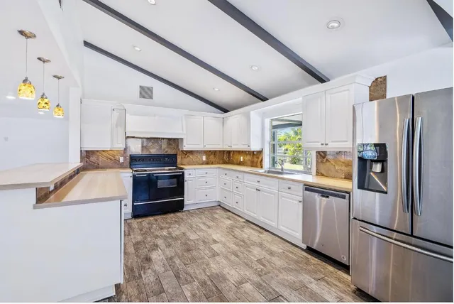 a kitchen with granite countertop a refrigerator stove and sink