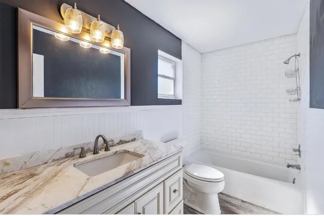 a bathroom with a granite countertop sink toilet and shower