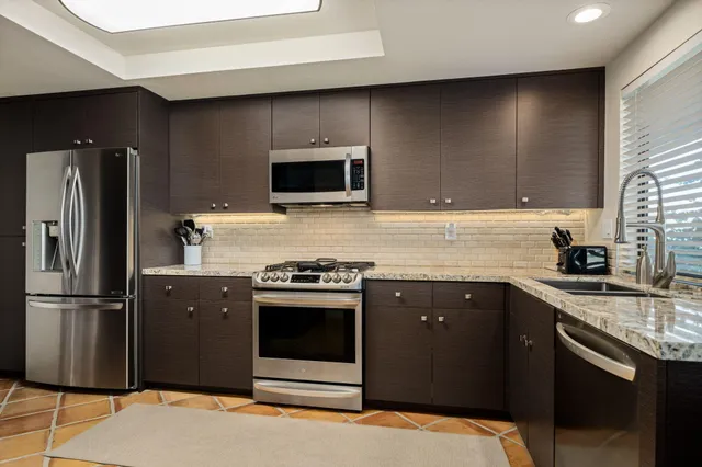 a kitchen with stainless steel appliances granite countertop a refrigerator stove a sink and dishwasher