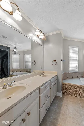 a spacious bathroom with a granite countertop double vanity sink a mirror and a bathtub