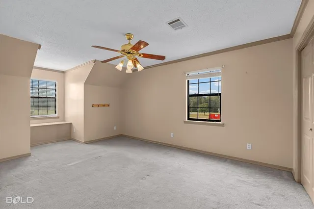 an empty room with windows and chandelier fan