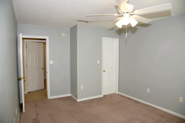 an empty room with a chandelier fan and closet