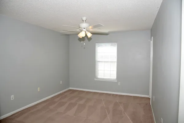 an empty room with windows and fan