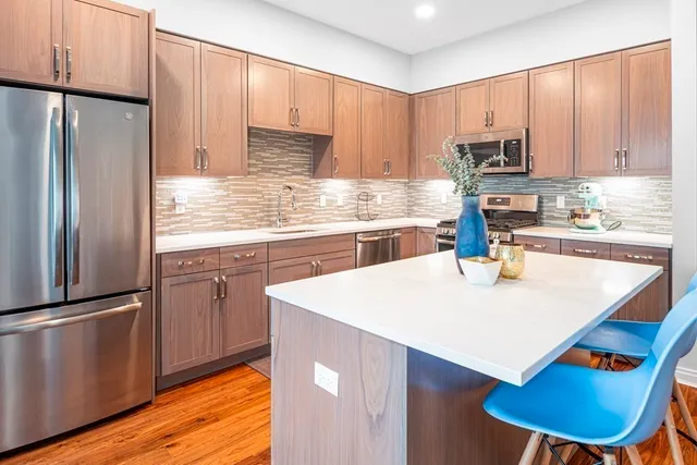 a kitchen with stainless steel appliances granite countertop a refrigerator a stove and a sink with wooden floors