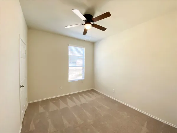 an empty room with a ceiling fan and window