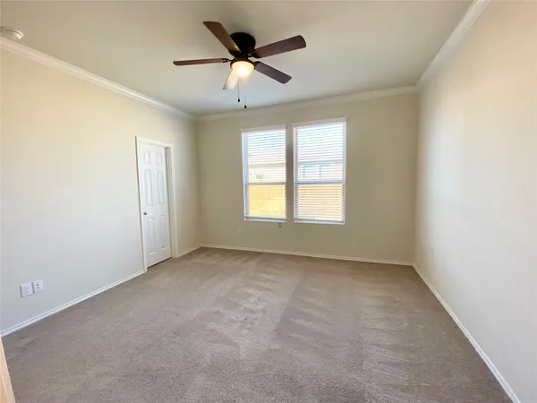 an empty room with a chandelier fan and windows