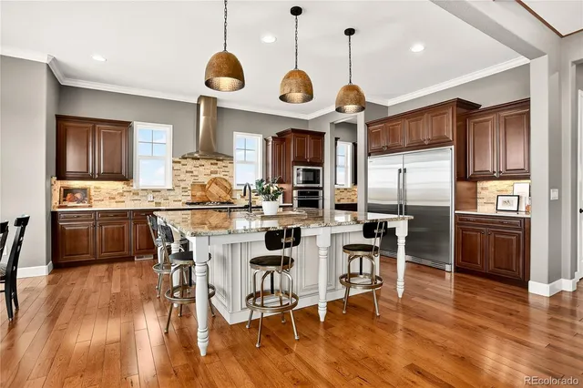 a kitchen with stainless steel appliances a dining table chairs stove and refrigerator