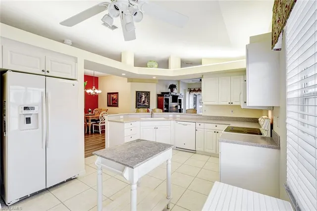 a large white kitchen with cabinets and chairs