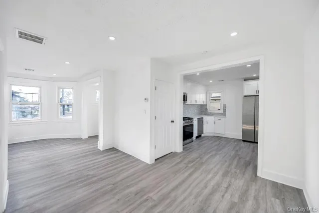 a view of a big room with wooden floor and a kitchen