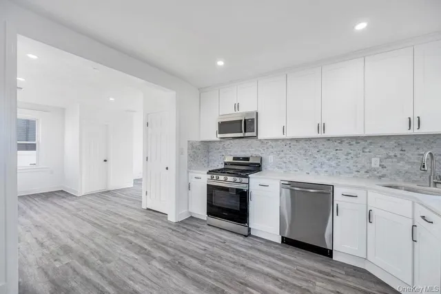 a kitchen with granite countertop white cabinets and stainless steel appliances
