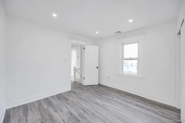 an empty room with wooden floor and window