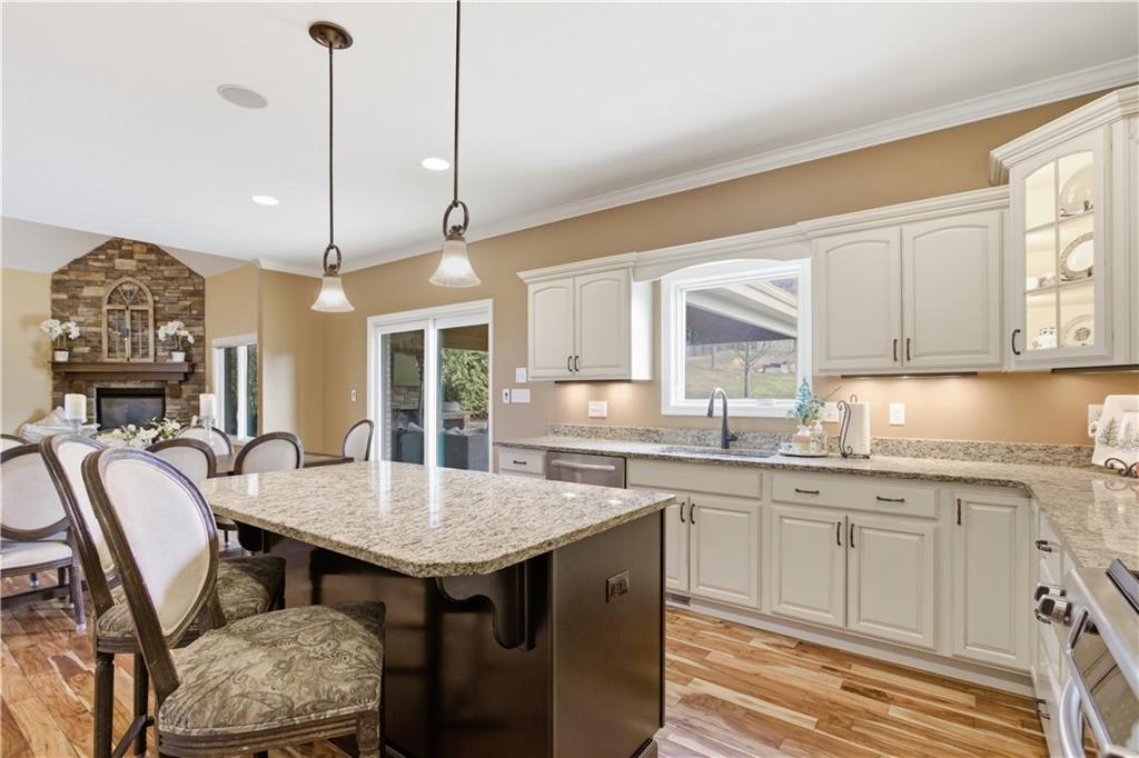 280 Sienna Trail Venetia, PA 15367 - Photo 17 of 37 a open kitchen with granite countertop a stove a sink a dining table and chairs with wooden floor