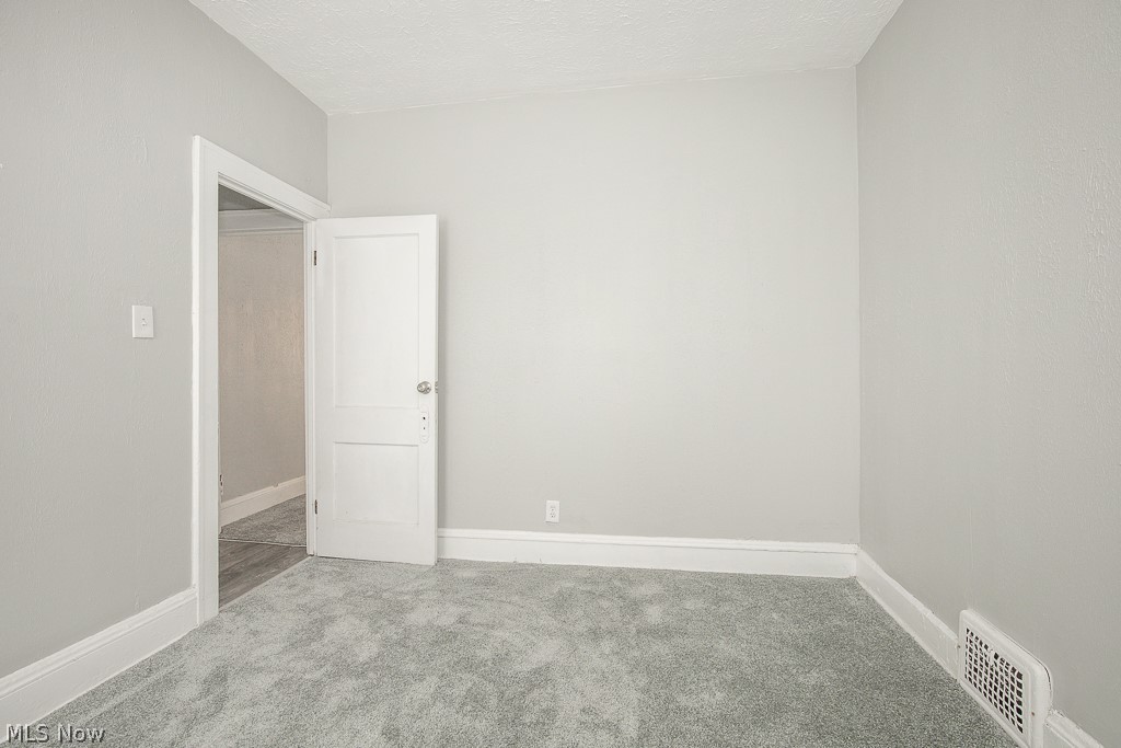 1000 Eddy Road Cleveland, OH 44108 - Photo 15 of 38 Carpeted spare room featuring baseboards and a textured ceiling
