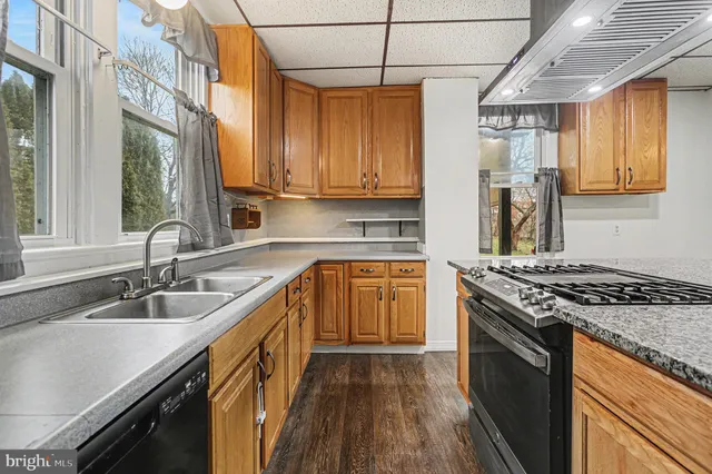 a kitchen with granite countertop a sink a counter space appliances and cabinets