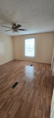 an empty room with wooden floor chandelier fan and windows