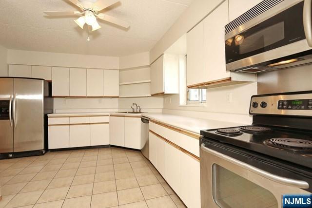 1055 River, Unit 506 Edgewater, NJ 07020 - Photo 7 of 25 a kitchen with stainless steel appliances a sink a stove and a microwave