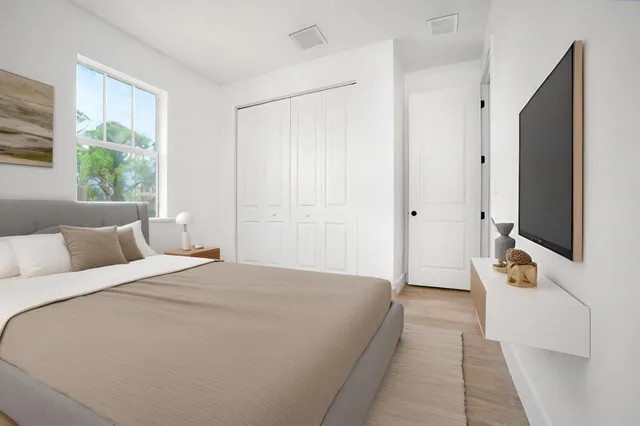 a spacious bedroom with a bed and a flat tv screen