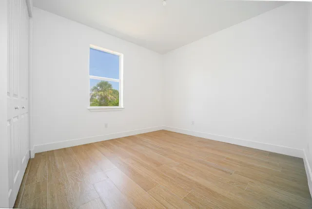 an empty room with wooden floor and window
