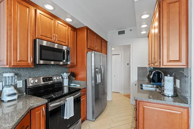 a kitchen with stainless steel appliances granite countertop a refrigerator stove and sink