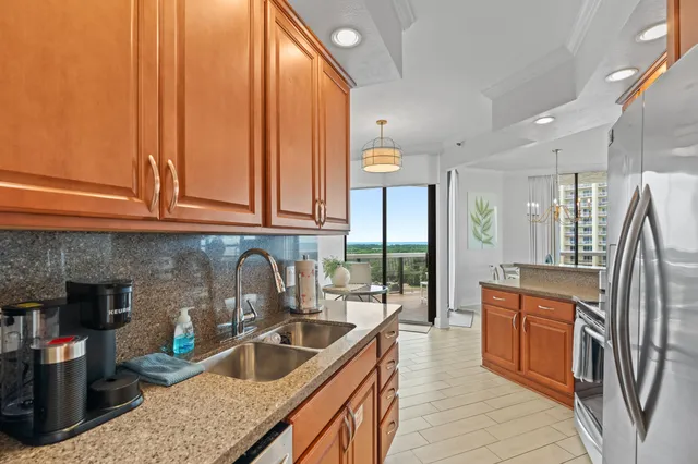 a kitchen with stainless steel appliances granite countertop a sink a stove and a wooden cabinets
