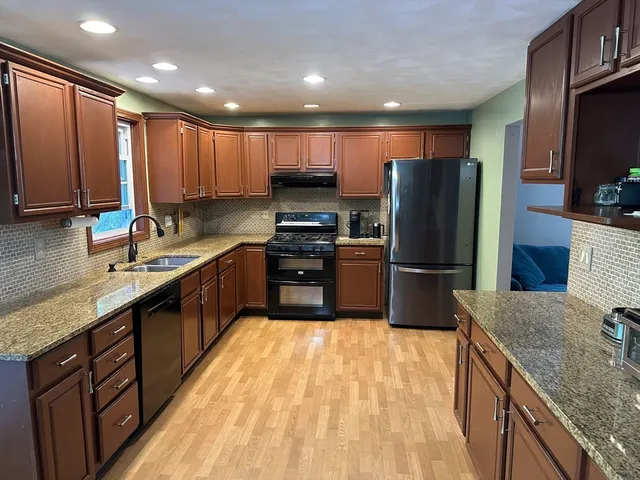 a kitchen with kitchen island granite countertop a sink stainless steel appliances and cabinets