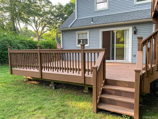 a view of a house with backyard and wooden deck