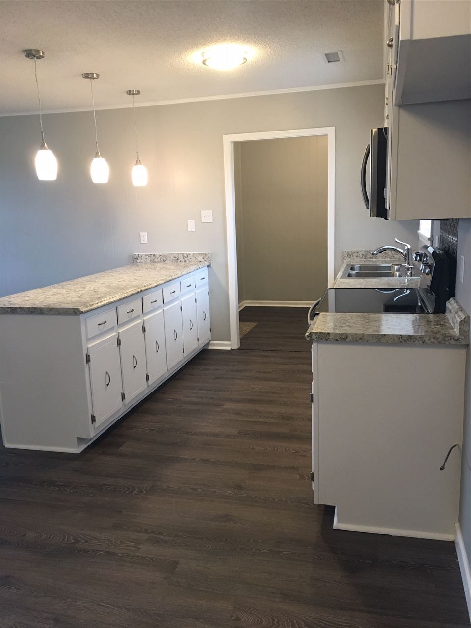 1548 Oil Mill Road Covington, TN 38019 - Photo 8 of 9 nice galley kitchen with new smooth-top electric stove and built-in microwave oven. Through the door is the laundry room.