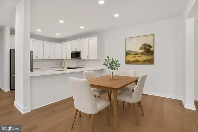 a kitchen with stainless steel appliances granite countertop a dining table chairs and a refrigerator