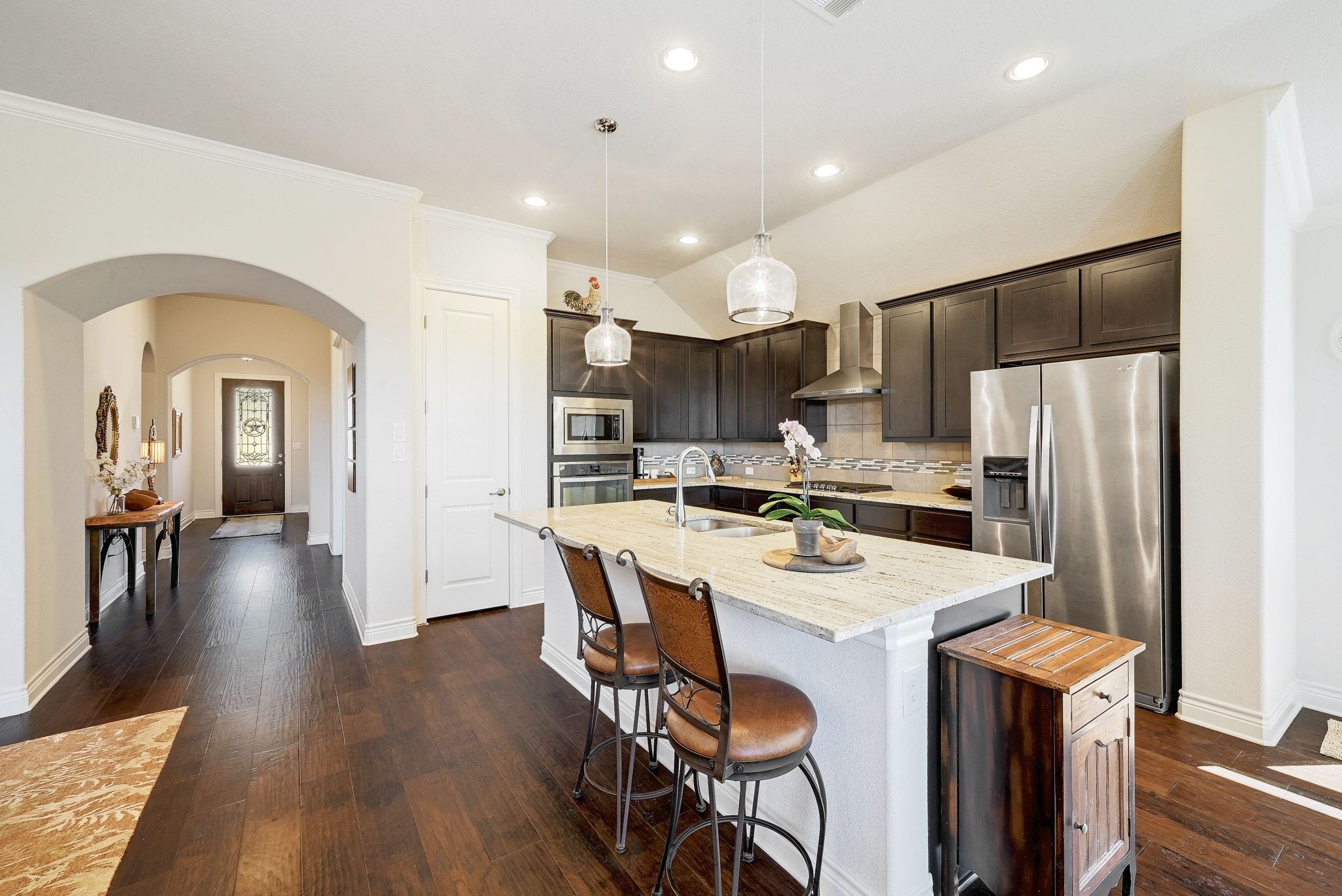 960 Blue Ridge Drive Dripping Springs, TX 78620 - Photo 6 of 38 Kitchen with dark wood finish cabinets, arched walkways, light stone countertops, stainless steel appliances, and tasteful backsplash