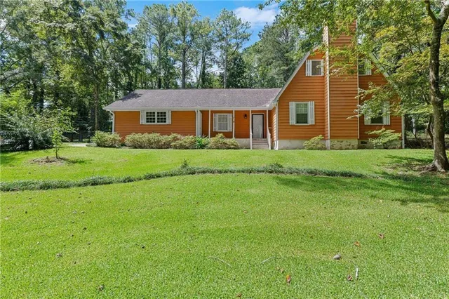 a view of a yard in front of a house with large trees