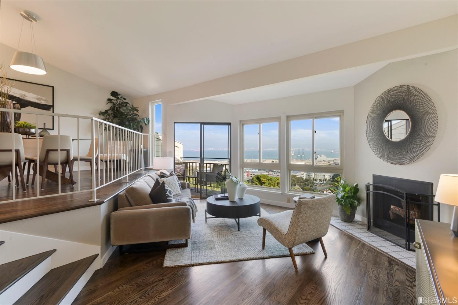 An open living/dining area with fireplace, gorgeous wood floors, and spectacular views.